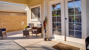 A patio with wicker furniture, a potted plant, and a sliding glass door. - Golf, Hikes & Sports Fun! Desert Getaway w/ Pool (Goodyear)