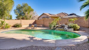 A backyard with a swimming pool, patio furniture, and a brick wall. - Golf, Hikes & Sports Fun! Desert Getaway w/ Pool (Goodyear)
