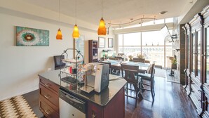 Una cocina amplia con una isla central, iluminación colgante y un ventanal que proporciona luz natural.