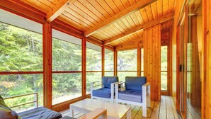 A wooden cabin with large windows, a sofa, and a table. - Luxe 5,000 Sq Ft Retreat: 5 Mi to Stratton Resort (Jamaica)