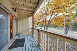 Une terrasse en bois offrant une vue sur les arbres aux couleurs automnales et une rivière.