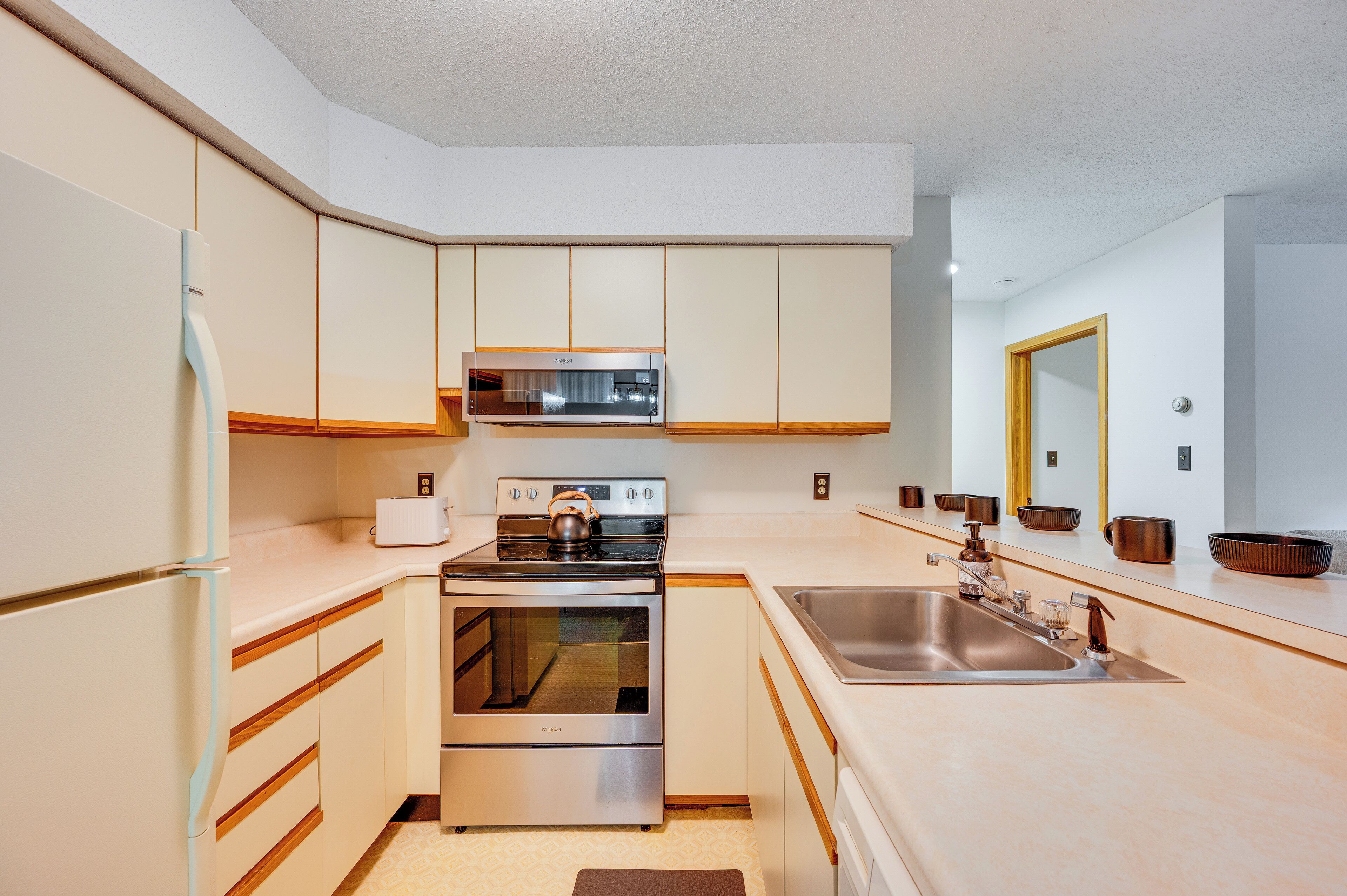 Una cocina moderna con electrodomésticos de acero inoxidable, armarios de madera y un espejo grande sobre el lavabo.