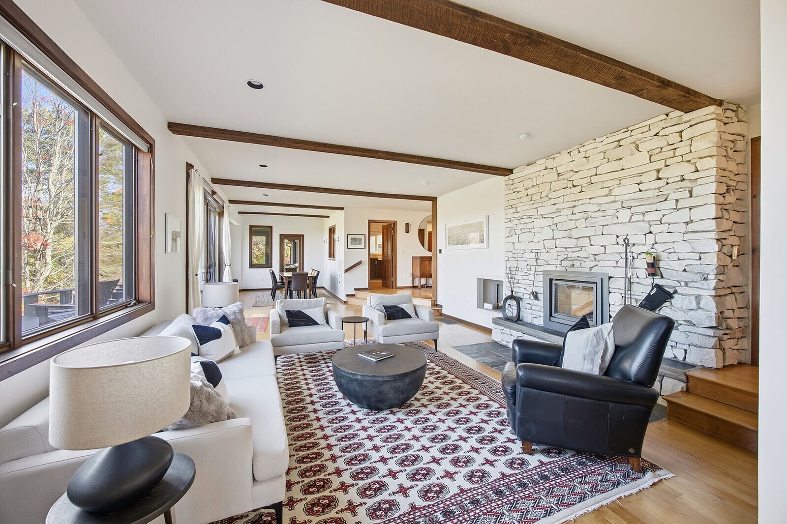 A modern living room with a stone wall, a fireplace, and a large window.