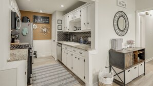 Een moderne keuken met witte kasten, een zwarte spatwand en een centraal eiland.