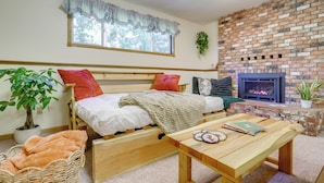 A cozy bedroom with a bed, a wooden table, a potted plant, and a brick fireplace. - Near Olympic NP, Beaches! Nature Lover's Farmhouse (Port Angeles)