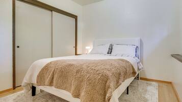 A bedroom with a bed, a large closet, a nightstand, and a lamp.