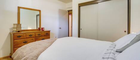 A bedroom with a bed, dresser, mirror, and a door.