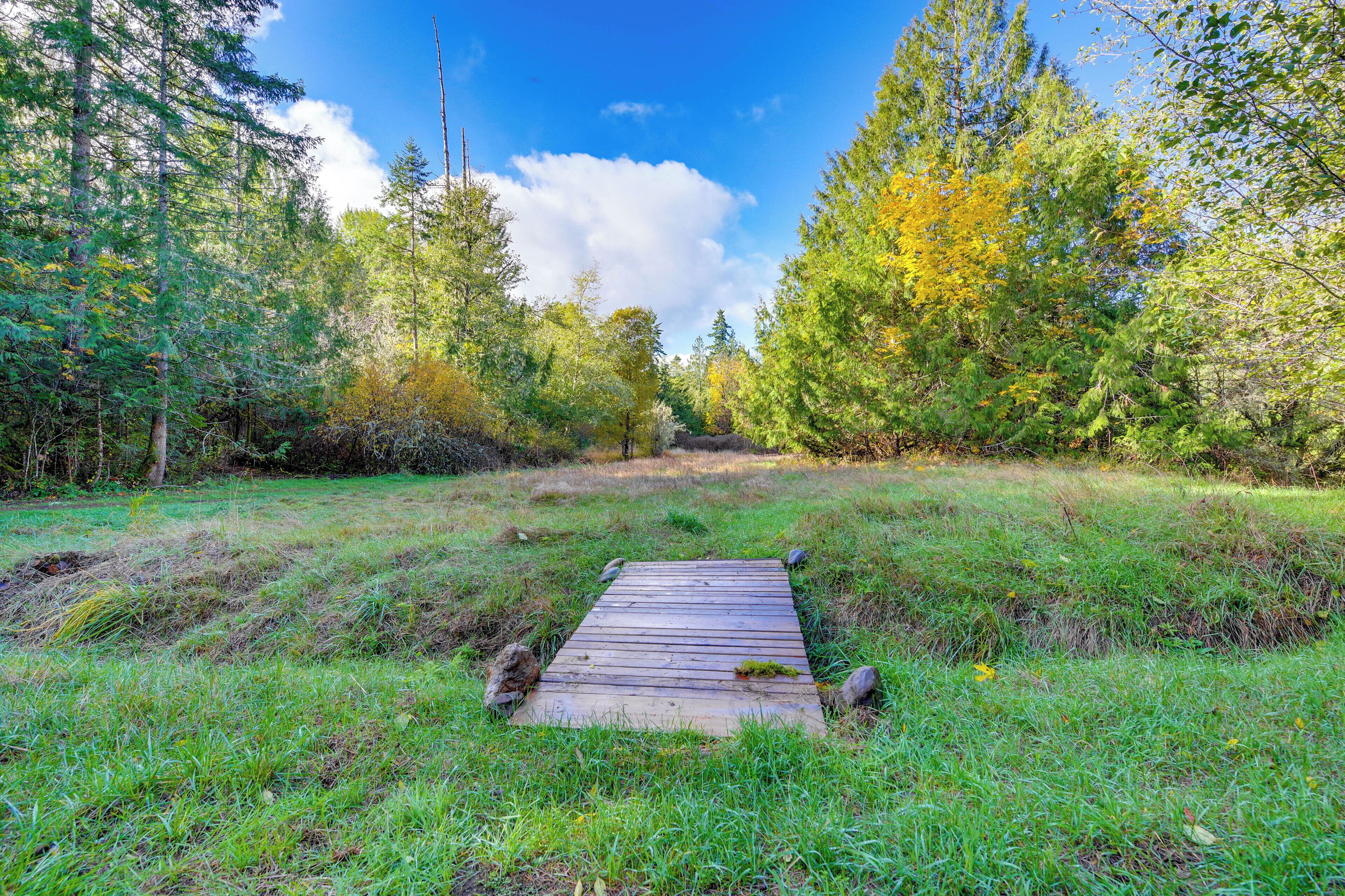 A wooden bridge in a forested area with a clear sky.