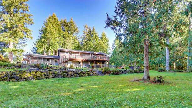 A two-story house with a balcony, surrounded by a well-maintained lawn and tall trees. - Near Olympic NP, Beaches! Nature Lover's Farmhouse (Port Angeles)