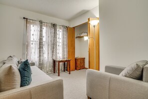A living room with a sofa, a small table, and a wooden cabinet. - 12 Mi to Dtwn St Paul: Extended Stay in Woodbury! (Woodbury)