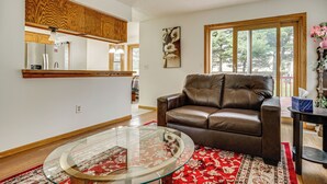A living room with a leather sofa, a glass coffee table, and a red patterned rug. - 12 Mi to Dtwn St Paul: Extended Stay in Woodbury! (Woodbury)