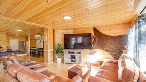 Un interior de madera con sofás de cuero, una mesa de billar y un televisor.