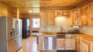 A modern kitchen with wooden cabinets, stainless steel appliances, and a brick backsplash.