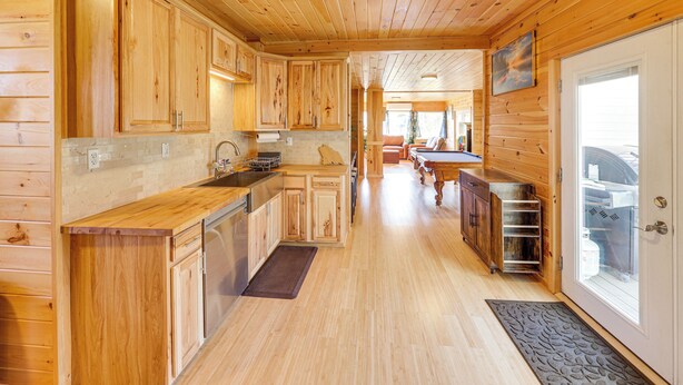 Interior de una cabaña de madera con cocina, comedor y una puerta que da a un garaje.