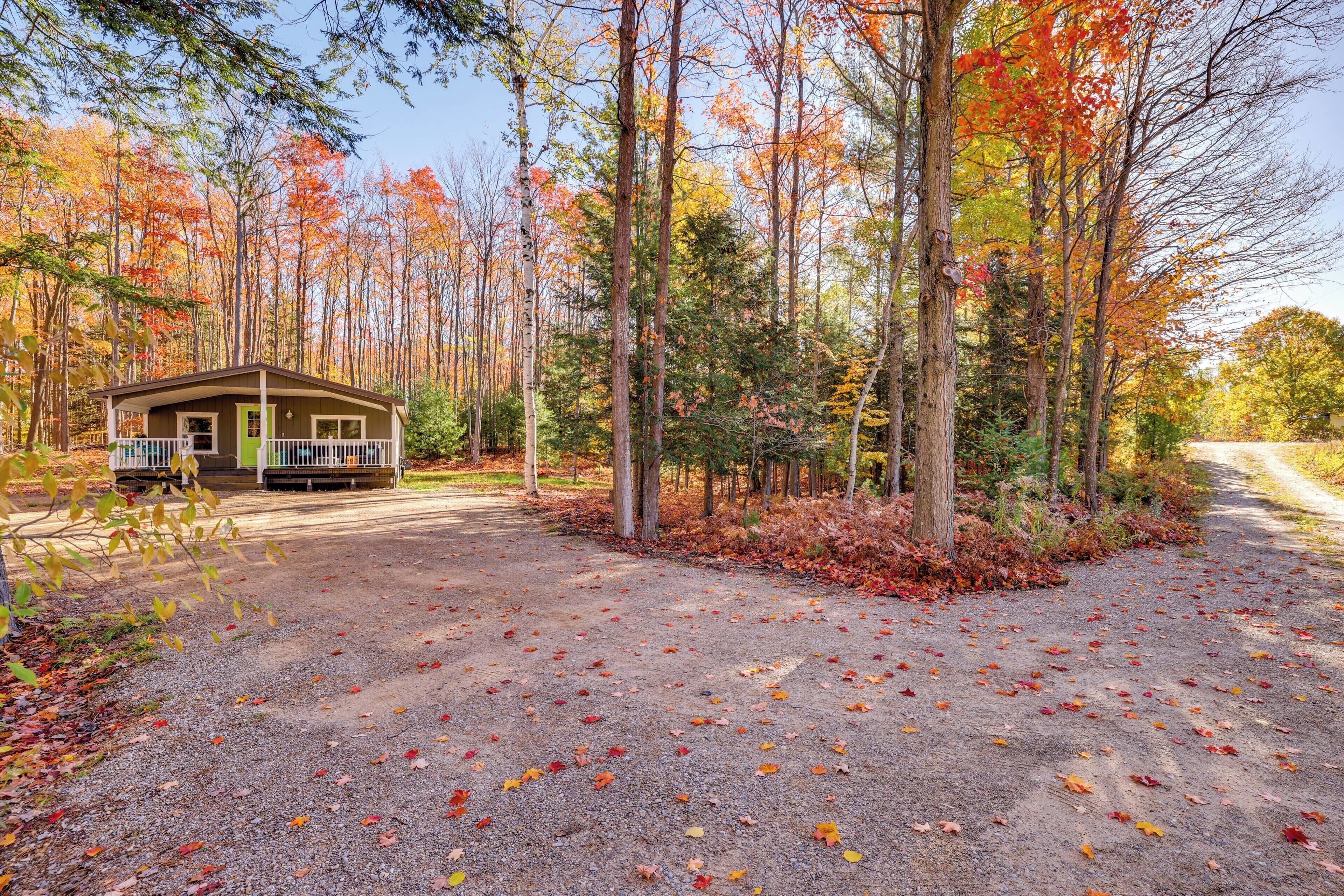 Een chalet met een veranda, omgeven door een bos met herfstkleuren.