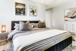 A modern bedroom with a large bed, a bedside lamp, and artwork on the walls. - 2 Mi to Uscg Academy! Convenient New London Home (New London)