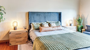 Un dormitorio moderno con una cama grande, mesitas de noche de madera y un ventilador de techo.