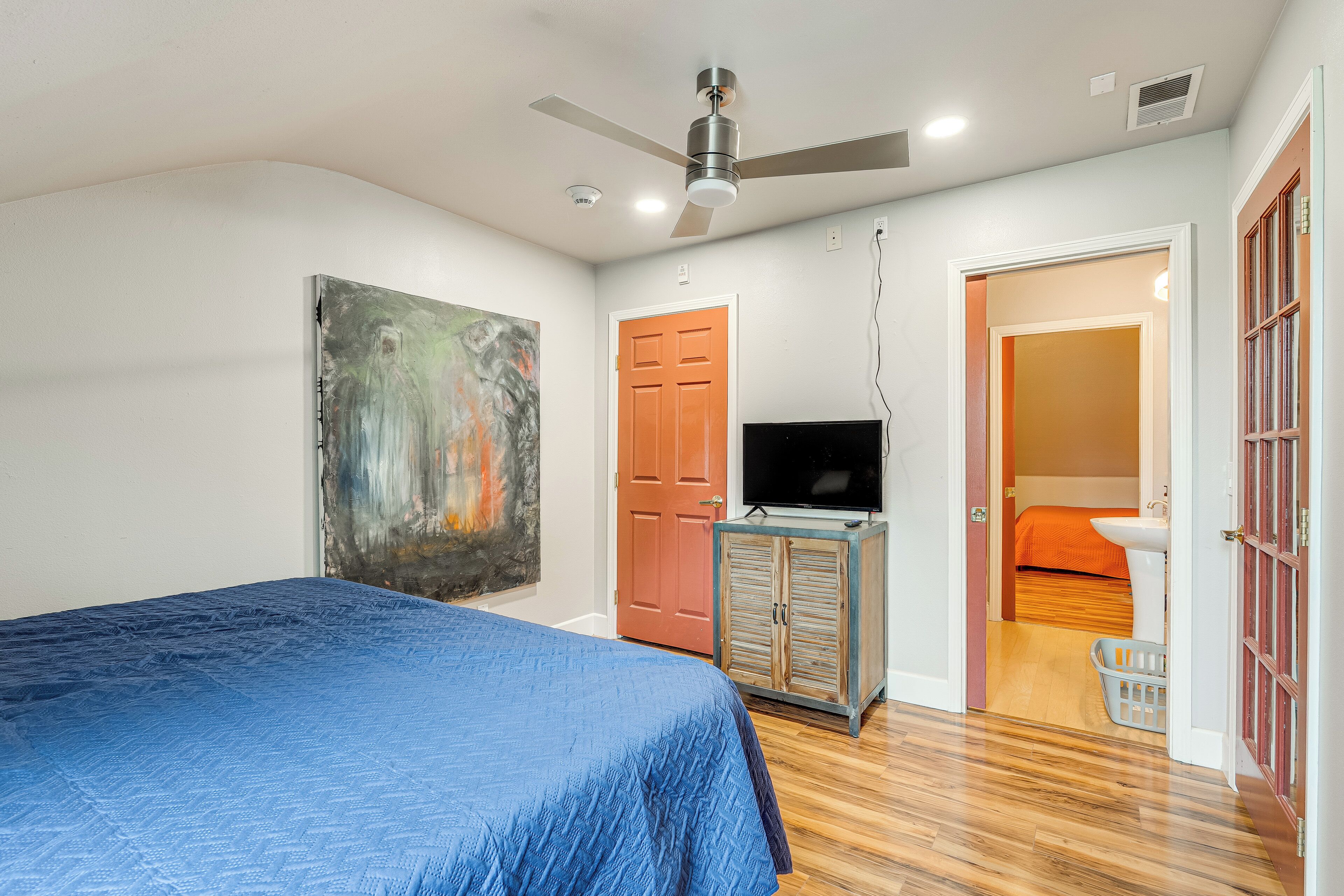 A bedroom with a bed, a television, a wardrobe, and a door leading to a bathroom.