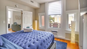 Une chambre à coucher avec un grand lit, une chaise et une fenêtre équipée de stores.