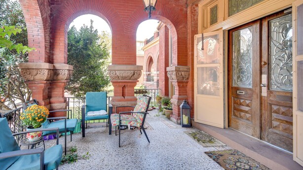 Une terrasse avec des sièges extérieurs, une arche en briques et une porte en bois dotée de panneaux de verre.