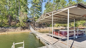 A wooden dock extending into a river, with a covered seating area and a boat docked on the right. - Clark's Hill Lake Retreat! Waterfront Home w/ Dock (Modoc)