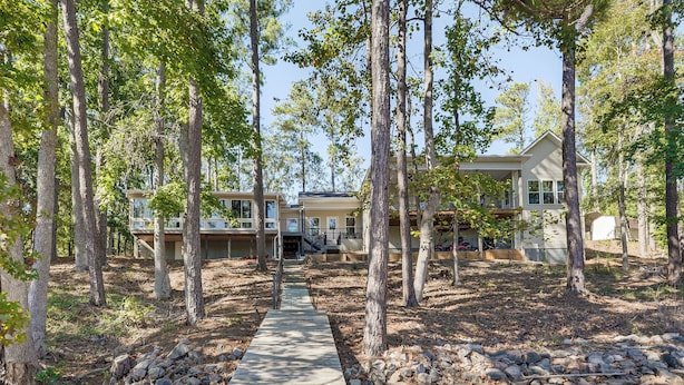 A pathway leading to a two-story house surrounded by tall trees. - Clark's Hill Lake Retreat! Waterfront Home w/ Dock (Modoc)