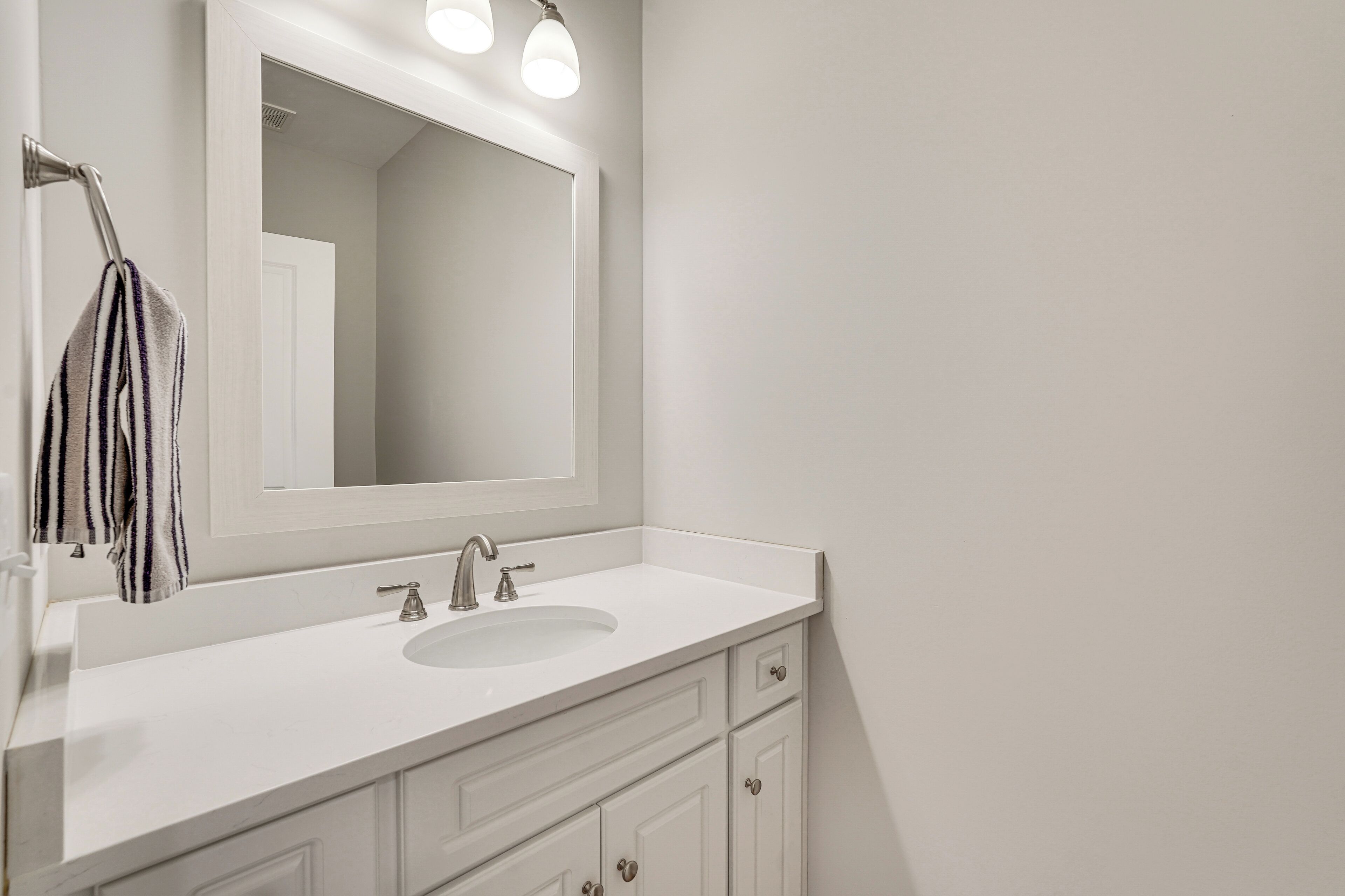 A modern bathroom with a white vanity, a large mirror, and a single sink.