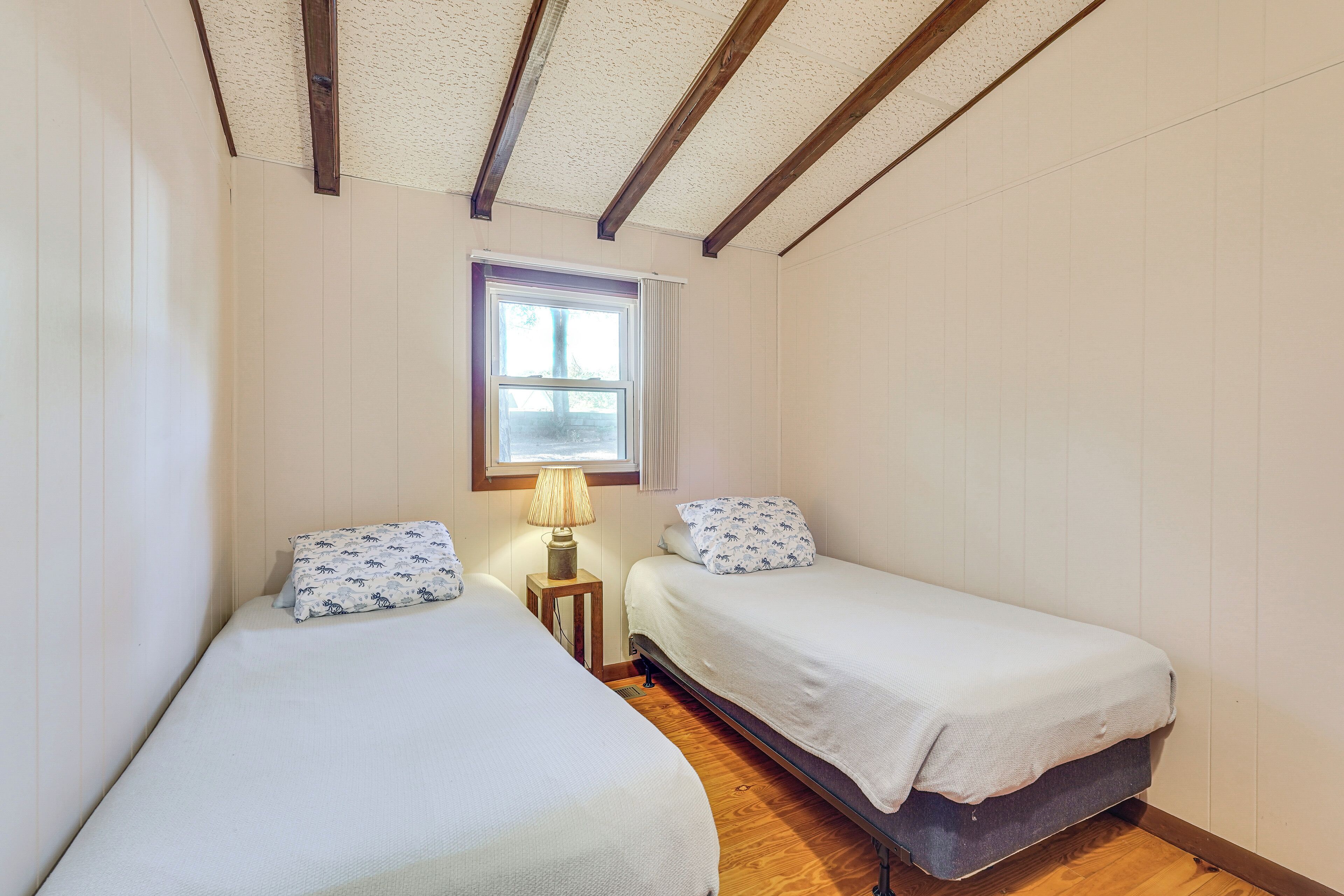 A small, cozy room with two single beds, a window with a view, and a wooden floor.