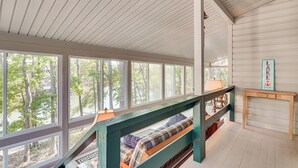 A spacious room with large windows, a wooden bench, and a small table. - Clark's Hill Lake Retreat! Waterfront Home w/ Dock (Modoc)