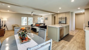 A modern kitchen with a central island, a dining area with a table and chairs, and a living room with a sofa and a coffee table. - Hunt, Fish & Relax: Rural Retreat in Green Pond (Jacksonboro)