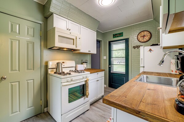 A kitchen with white cabinets, a stove, a wooden countertop, and a sink. - Iroquois River Retreat! Waterfront Cabin w/ Deck (Ashkum)
