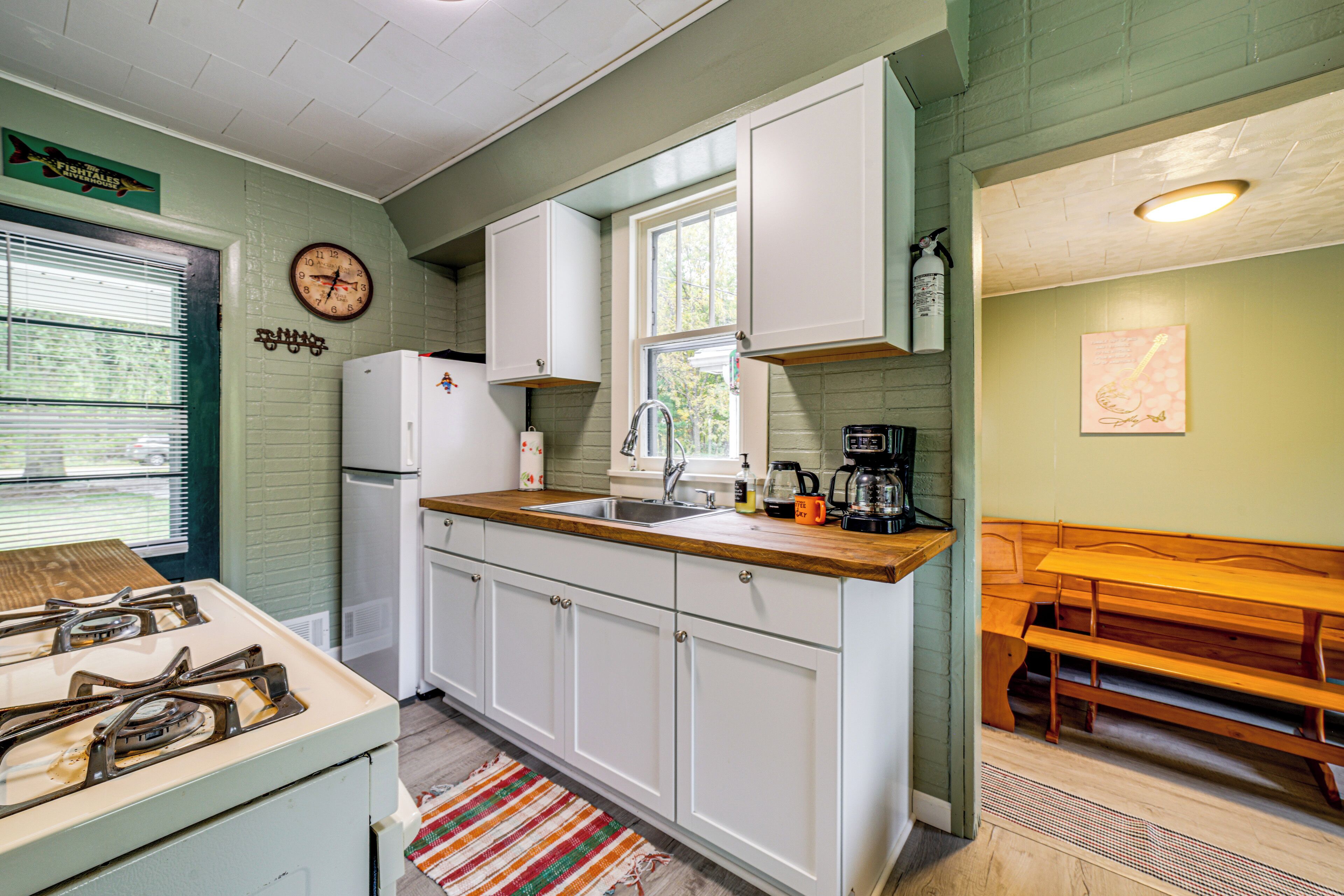 Una cocina con armarios blancos, encimera de madera, estufa y lavabo.