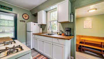 Una cocina con armarios blancos, encimera de madera, estufa y lavabo.