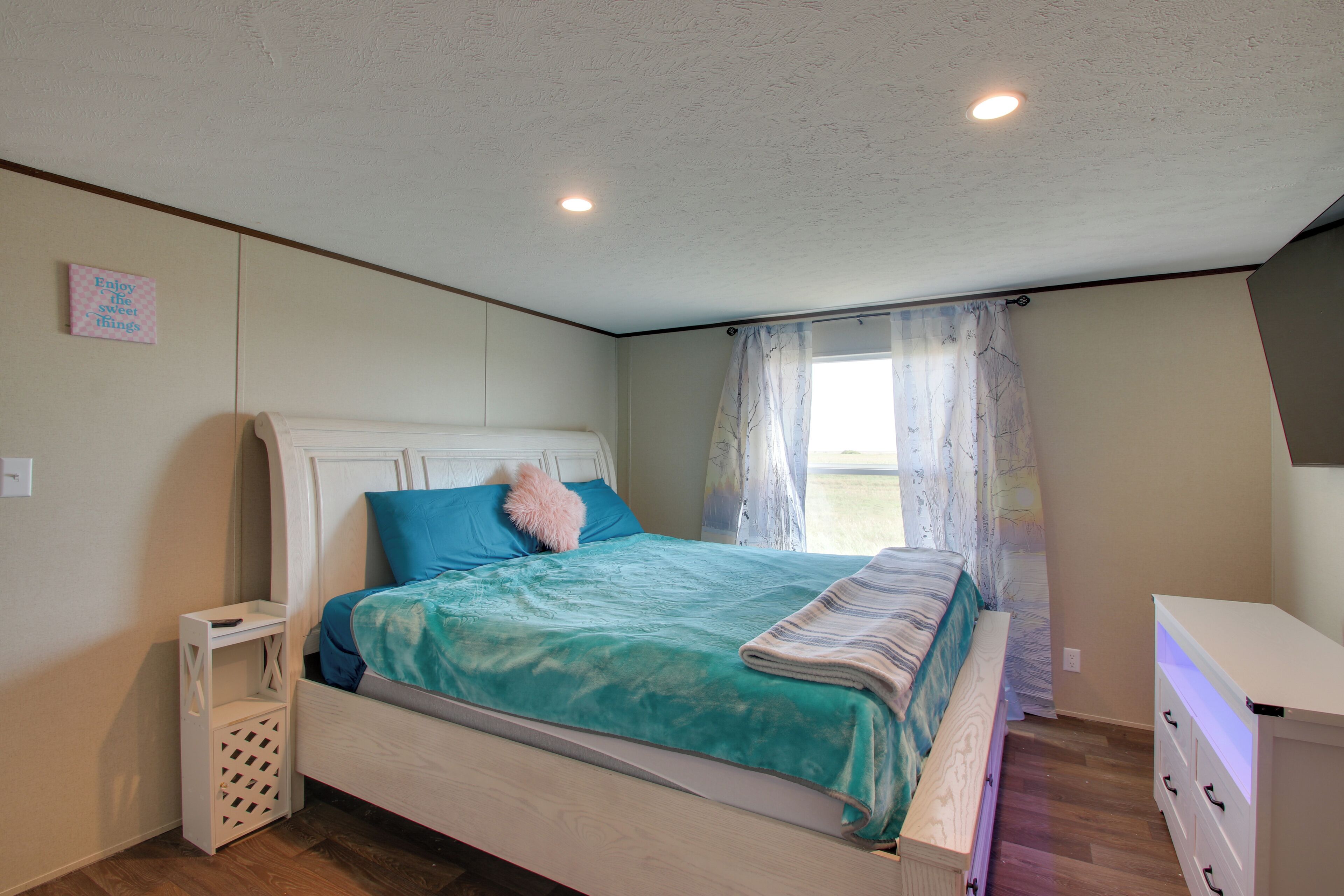 A bedroom with a bed, a bedside table, a nightstand, and a dresser.