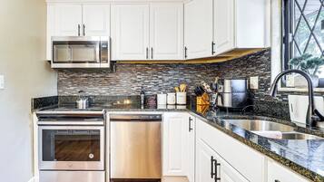 A kitchen with white cabinets, a stainless steel microwave, a stove, and a dishwasher.