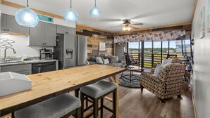 A modern kitchen with a wooden island, grey cabinets, and a view of a balcony with a railing. - Walkin on Sunshine! Marshside Inn 309 (Murrells Inlet)