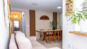 Een moderne woonkamer met een bank, eettafel, stoelen en een potplant.