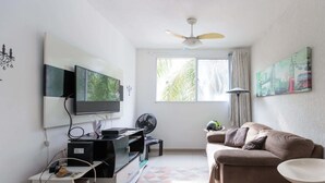 Un salon équipé d’un téléviseur, d’un ventilateur de plafond, d’un canapé et d’œuvres d’art accrochées au mur.