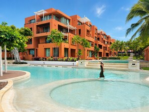 A modern hotel with a pool, palm trees, and a clear blue sky. - Hua Hin Beach Front Condo - Family Suite Room at Las Tortugas (Tambon Nong Kae)