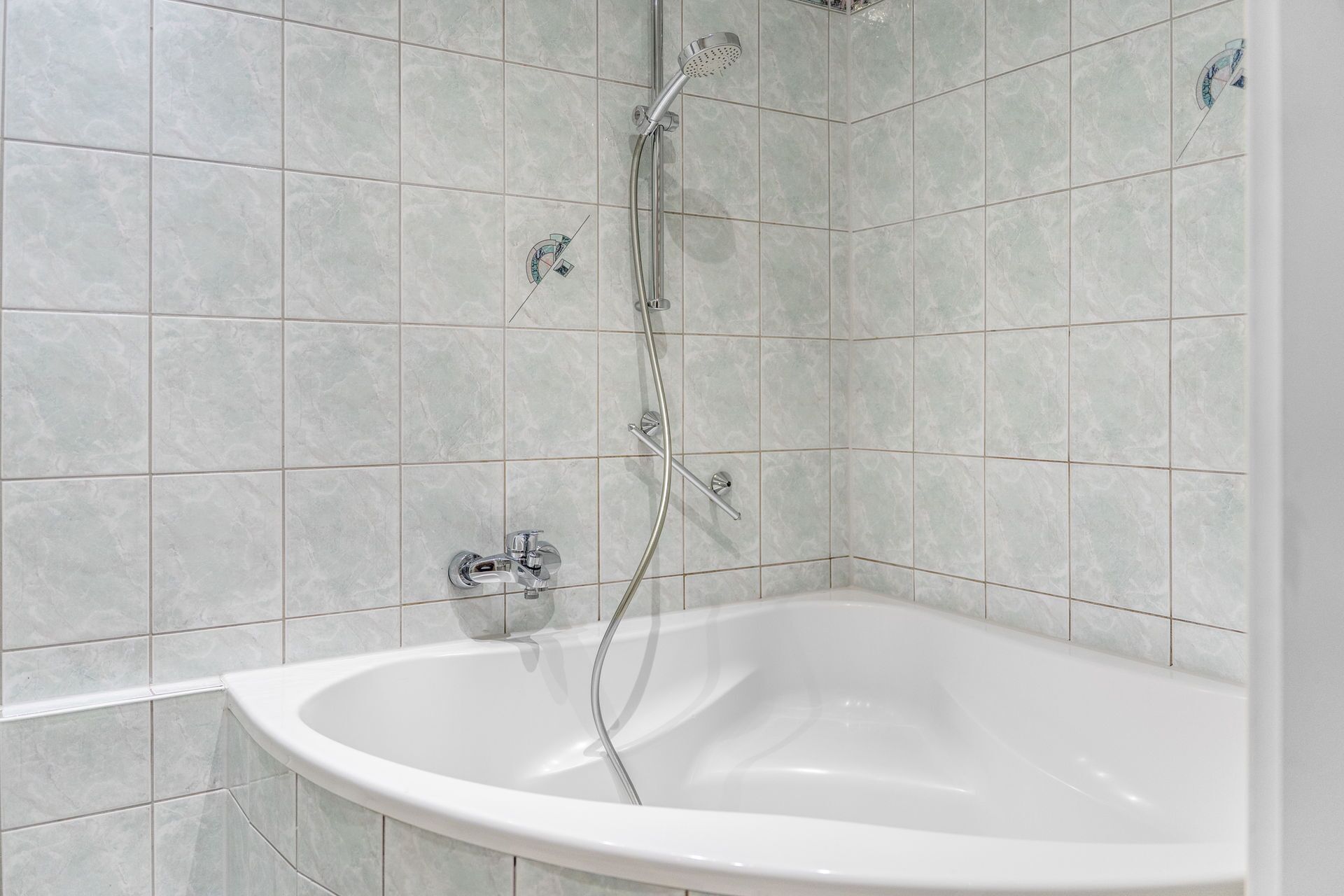 Une salle de bain moderne avec une baignoire sur pieds, une douchette et un robinet mural.