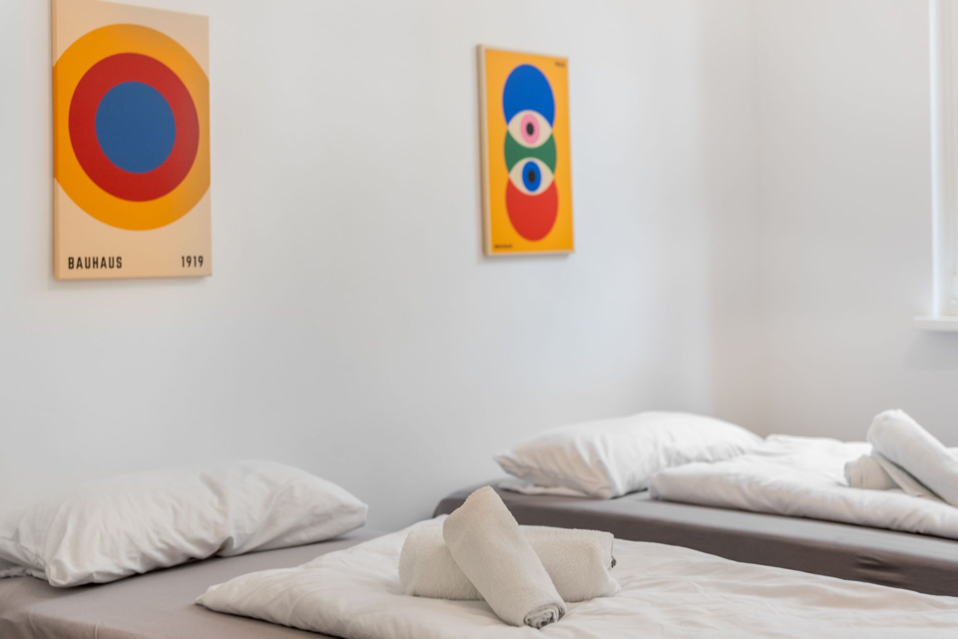 A hotel room with two beds, white bedding, and artwork on the walls.