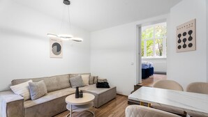 A modern living room with a sofa, a round coffee table, and a dining area with a table and chairs. - EXQUIS Luxus 3-Room Maisonette I Stuttgart West Schwabstraße Train Station (Stuttgart)