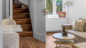 A modern living room with a wooden staircase, a round table, and a sofa. - EXQUIS Luxus 3-Room Maisonette I Stuttgart West Schwabstraße Train Station (Stuttgart)