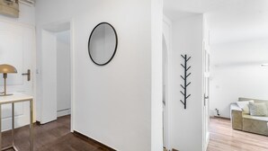 A hallway with a round mirror, a coat rack, and a table with a lamp. - EXQUIS Luxus 3-Room Maisonette I Stuttgart West Schwabstraße Train Station (Stuttgart)