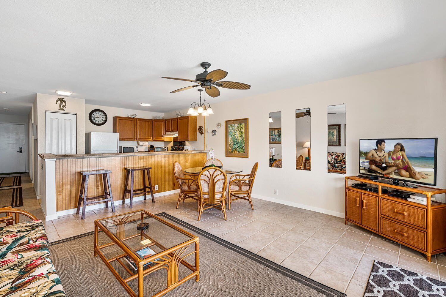 A spacious living area with a kitchen, dining table, and bar stools.