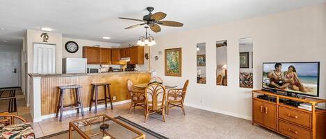A spacious living area with a kitchen, dining table, and bar stools.