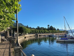 A marina with boats docked, a stone pathway, and a statue. - Villa Giulia - Vista Verde at 5 min from  the lake (Porto Valtravaglia)
