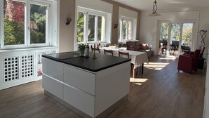 A spacious kitchen with a large island, white cabinetry, and a dining area with a table and chairs. - Villa Giulia - Vista Verde at 5 min from  the lake (Porto Valtravaglia)