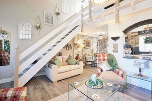A spacious living room with a staircase, a dining area, and a kitchen with a wine sign. - Host & Stay | The Cheeky Squirrel (New Brighton)