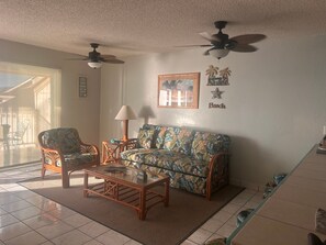 Ein Wohnzimmer mit einer Couch, Sesseln, einem Couchtisch und einem Deckenventilator.